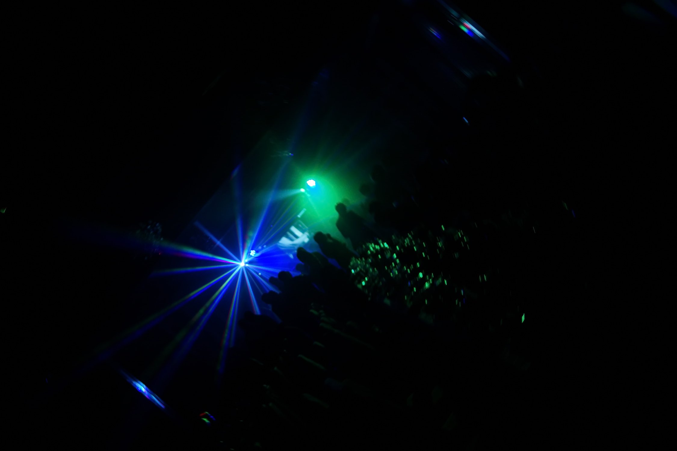 Deejay silhouette on a stage with big disco ball at background with the colorful rays on it