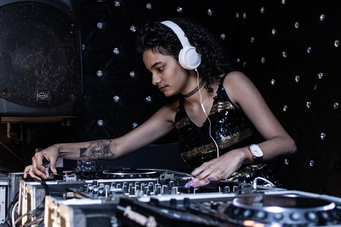 Focused ethnic female DJ playing music at nightclub